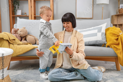 Young mother and her little son playing with toy airplanes at home