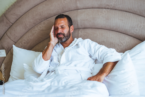 фотографія Relaxed Man In White Bathrobe Resting In Hotel Bed After Morning Spa Or Sleep