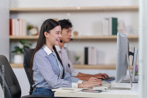 Asian female call center agent typing on computer keyboard at office desk