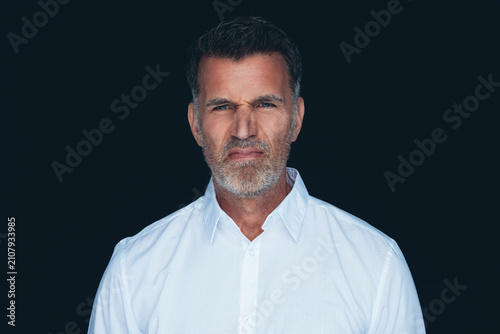 Portrait of man wrinkling nose in front of black background