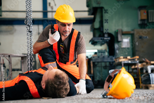 Factory worker using radio calling medical aid for unconscious coworker