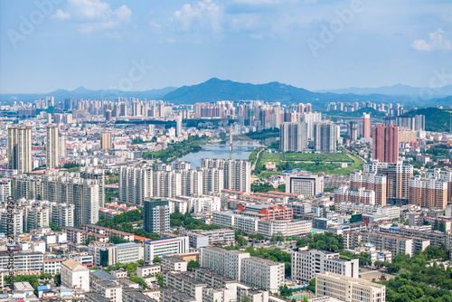 Foto A wide aerial panorama of a developed urban area with a river winding through it, backed by distant mountains under a clear blue sky
