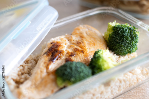 Grilled chicken breast with brown rice and broccoli in glass meal prep container. Close up