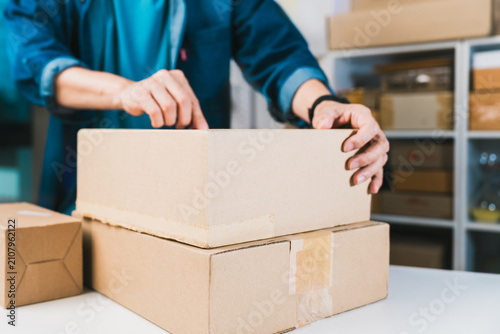 Person stacking cardboard shipping boxes at ecommerce fulfillment workspace