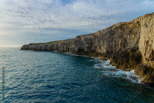 Cuadro en lienzo Dramatic coastal cliffs meet the wavy ocean under an overcast sky long rocks pan