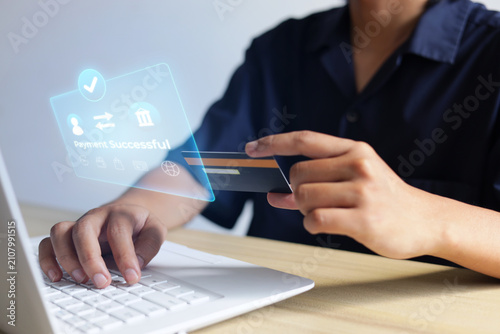 Person Typing On Laptop While Holding Credit Card With Display Showing Payment Successful Message