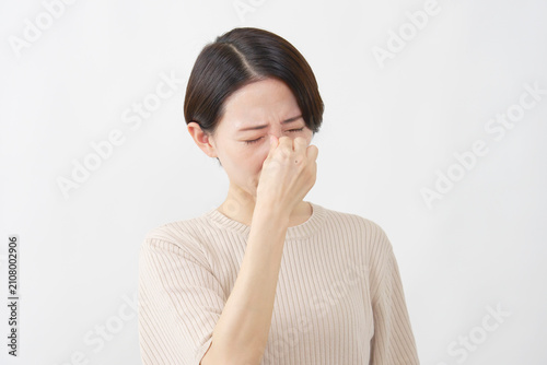 Foto 白背景で疲れ目を押さえる40代女性
