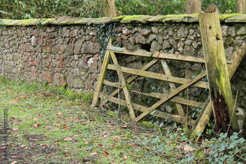 An Old Broken Wooden Farm Gate Against a Stone Wall.