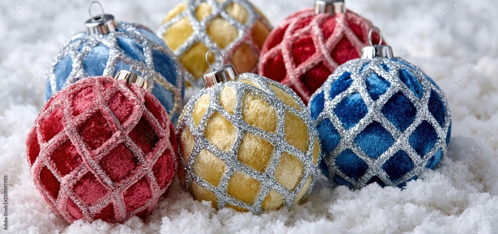 Fototapeta premium On a snowy backdrop, six vibrant velvet ornaments feature sparkling silver lattice designs ideal for festive decor.