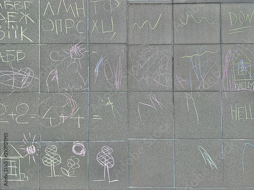 Educational background of children chalk drawings with alphabet, numbers and math on grey granite tiles.