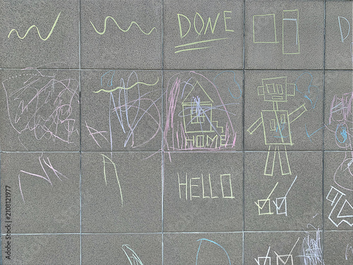 Abstract background of children chalk doodles and drawings of robot and house on a grey stone wall.