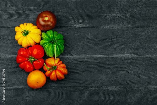 Quadro su tela Multicolored homegrown heirloom beefsteak tomatoes on a dark wooden background