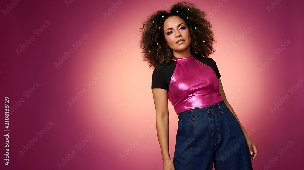 Obraz premium Stylish woman with curly hair and bold makeup poses against a vibrant pink and orange gradient background