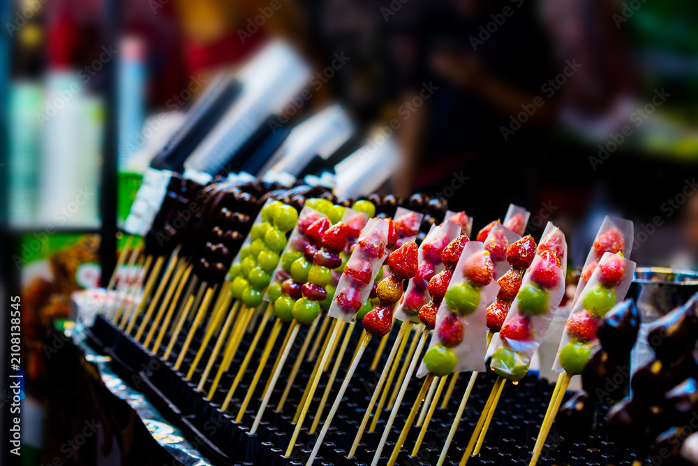 Fototapeta premium Candied fruit skewers Tanghulu on display at a lively Asian night market