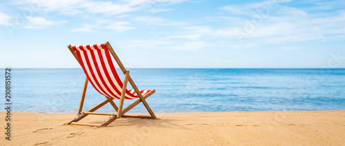 Fotografie Red striped deck chair on sandy beach