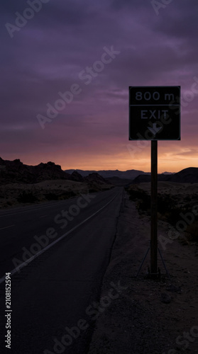 Dramatic Sunset Over Desert Highway with Exit Signage Guidance