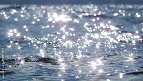 Sparkling sunlight glinting on ocean water surface.