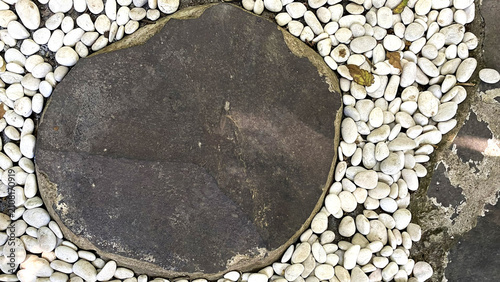 Fotografie Large dark stepping stone surrounded by white pebbles
