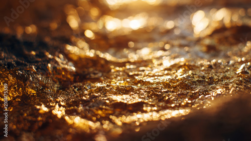 Close up of golden metallic texture with warm light reflections.