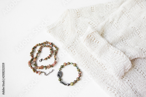 Картината върху платно A set of a necklace and a bracelet with jasper stones and a light-colored sweate