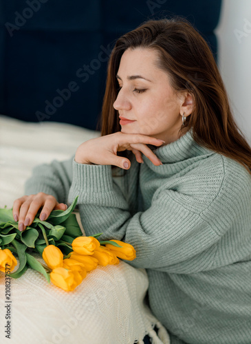 Woman with Yellow Tulips in Green Sweater. Cozy Bedroom Pose