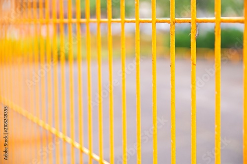 Fotografie Close up of yellow painted steel fence bars with selective focus and soft blurre