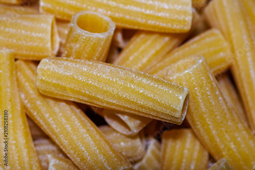 Konstfotografi Raw rigatoni pasta close-up, texture of dry Italian unbaked tubular pasta backgr