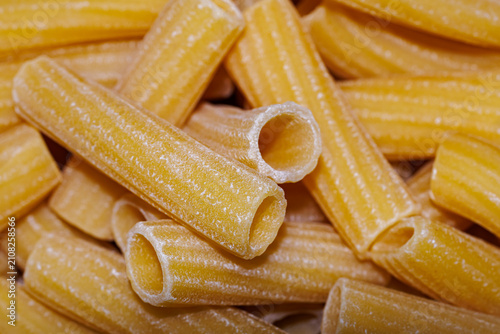Fotografie Raw rigatoni pasta close-up, texture of dry Italian unbaked tubular pasta backgr