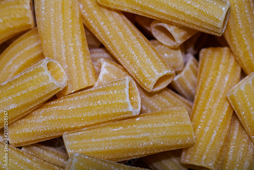 Bild auf Leinwand Raw rigatoni pasta close-up, texture of dry Italian unbaked tubular pasta backgr