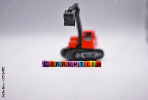 A toy excavator stands behind letter beads spelling 