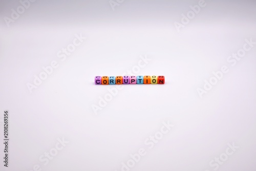 Colorful plastic letter beads spell out the word corruption centered against a clean, plain white background.