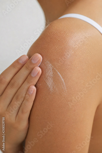 Woman applying sunscreen to shoulder skincare UV protection concept