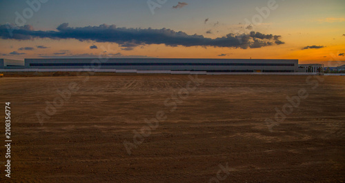 Fotografie Empty land plot prepared for industrial construction and warehouse development at sunset