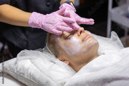 Tablou pe pânză Cosmetic physician performs a relaxing facial massage while applying nourishing skincare cream during a professional facial treatment in a modern beauty clinic to hydrate and rejuvenate the skin