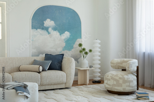 Modern living room interior with a cozy sofa, unique armchair, and cloud mural on a bright wall with natural light