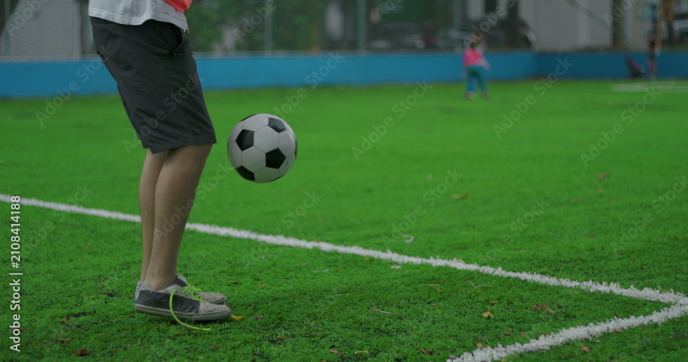 Obraz premium Young man juggling soccer ball on field performing around the world freestyle move, circling foot under ball and lifting it again with precision and rhythm during practice
