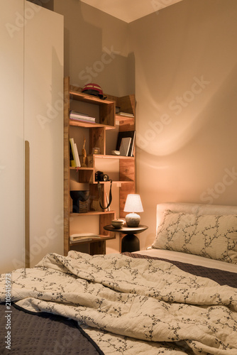 Cozy Bedroom Corner with Wooden Shelf, Bed, and Warm Lighting for Relaxing Home Interior