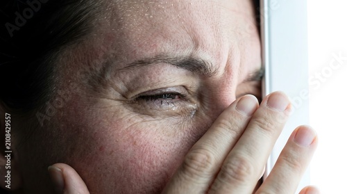 Crying woman looking out a window. Sad female face expressing grief and emotional pain.