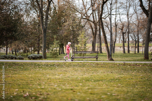 Foto Child enjoying playtime on scooter along a path in a park during autumn