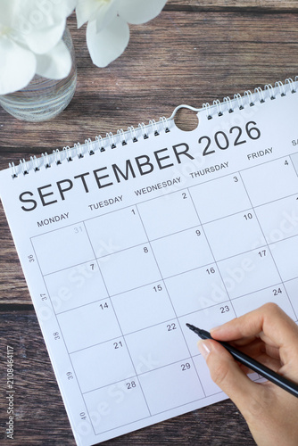 Hand holding a pen on top of September 2026 calendar.