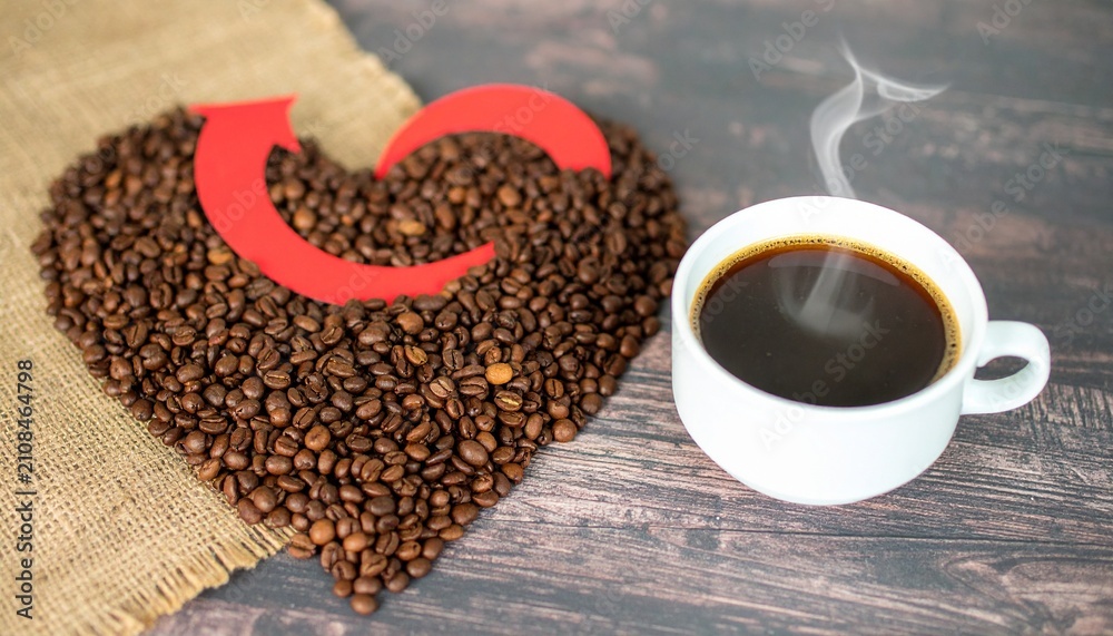 Naklejka premium Cup of coffee with heart shape smoke and coffee beans on burlap sack on old wooden