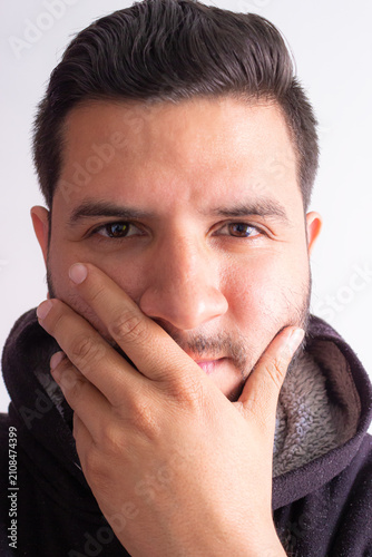 Foto Portrait of a young Latino man, impressed and with his mouth open, staring at the camera against a white background in a photography studio