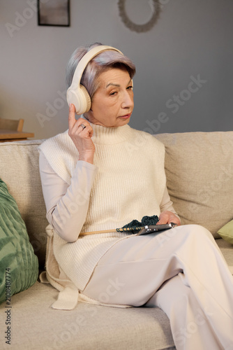 Foto Elegant senior woman enjoying music time at home in her cozy living room