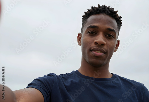 Young man taking selfie outdoors with cloudy sky