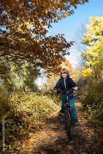 joyful boy, aged 9 10, rides a bicycle in a park with an autumn atmosphere. Active outdoor recreation, a happy childhood.