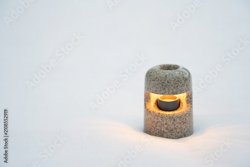 Small granite votive candle holder with lit candle, soft focus background