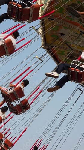 Visitors of the amusement park are enjoying the wave swinger ride. Visitors are excited to try the swing ride at the amusement park
