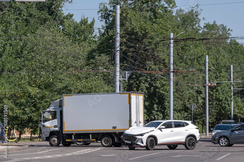 Road traffic accident involving a white SUV and a commercial box truck on a city street. Damaged automobile front, auto insurance claim, vehicle safety and collision concept.