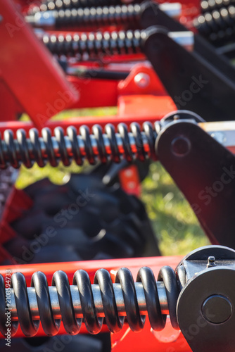 Steel black spring as part of heavy agricultural, industrial machine. Technology