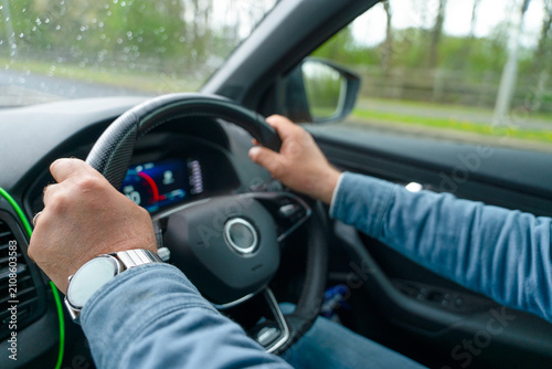 Driving a car on a rainy day with hands on the steering wheel